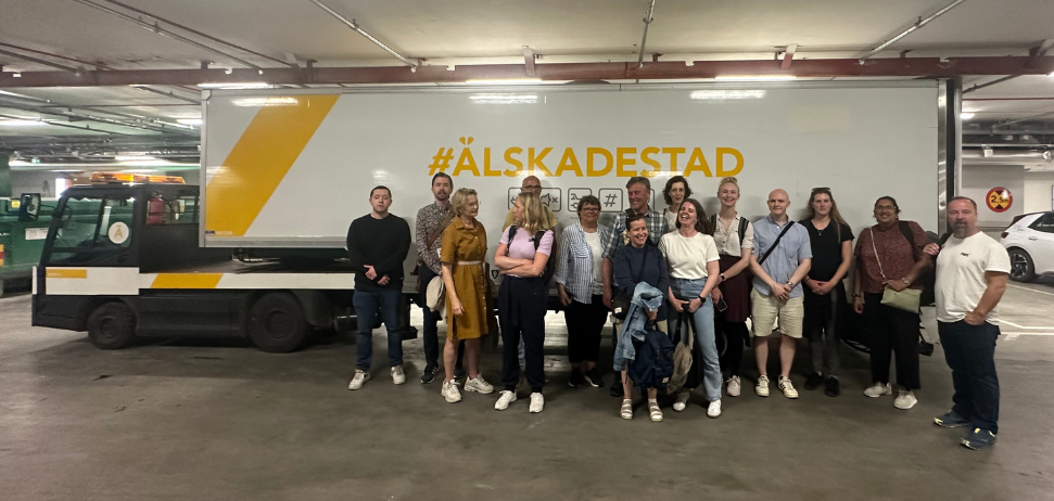 The photo shows a group in front of an electric delivery truck with the text Älskadestad.