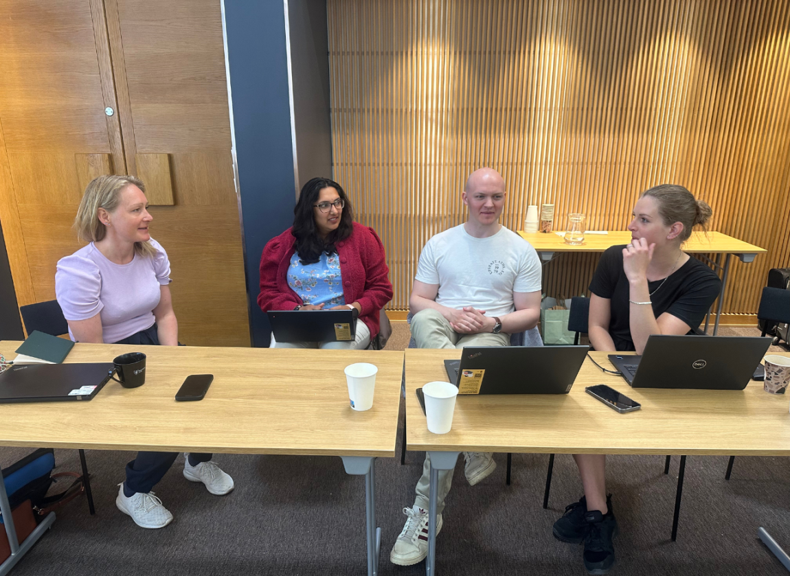 A group of four adults sitting and working together